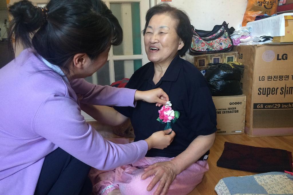 독거어르신들에게_카네이션을_달아주고_있다