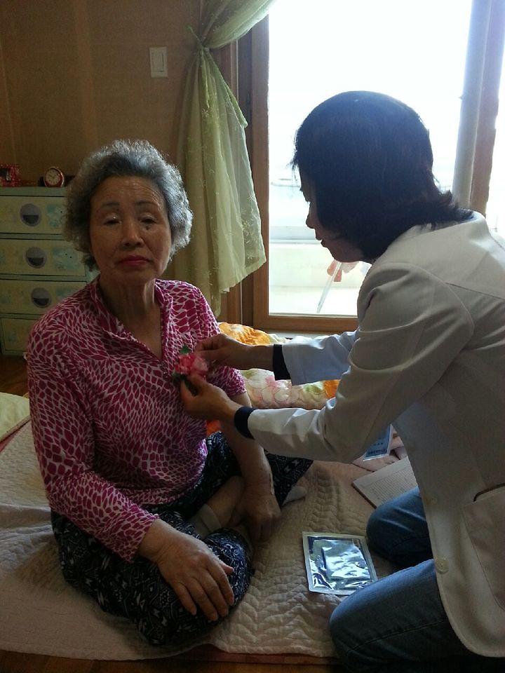 어버이날을_맞이하여_독거어르신에게_카네이션을_달아드리고_있다