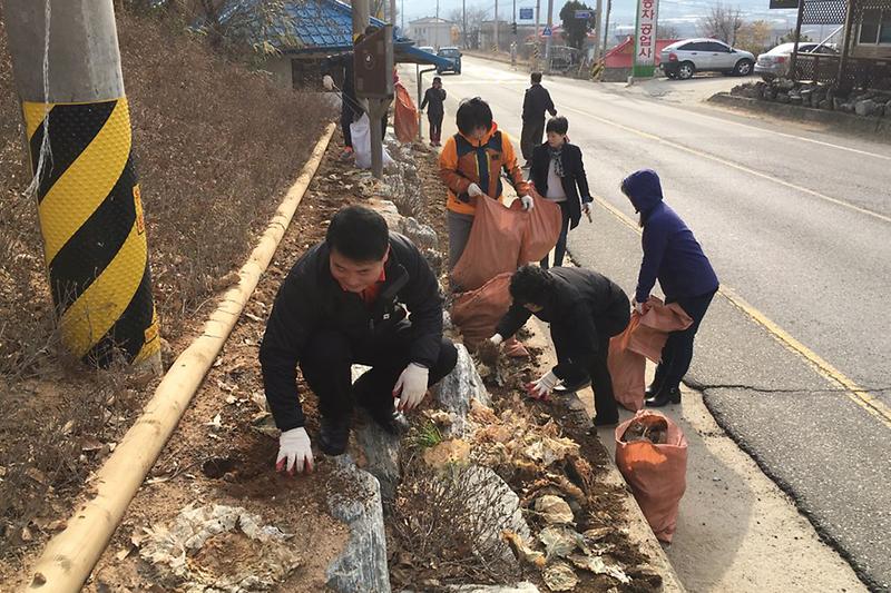 하점면주민자치위원회_위원들이_도로변을_청소하고_있다