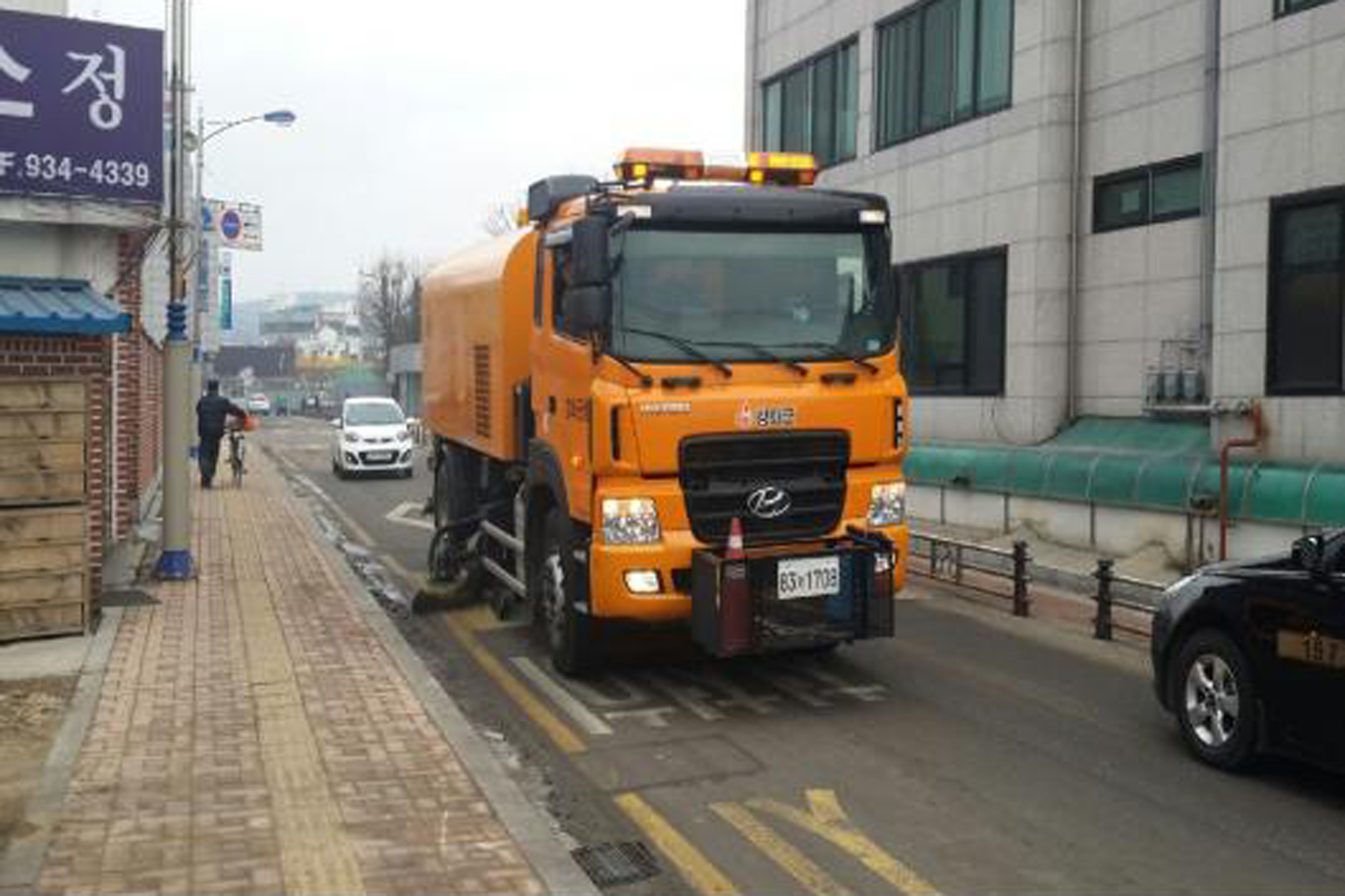 노면_청소_차량이_도로에_뿌려진_모래를_제거하고_있다